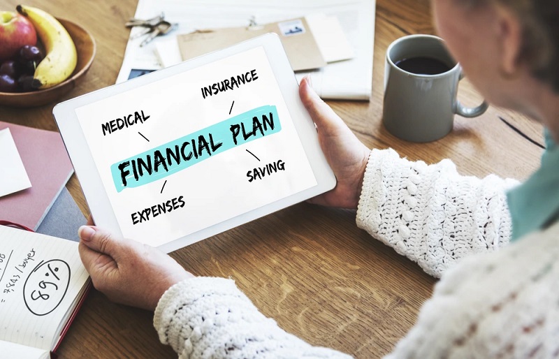 Person holding a tablet showing a financial plan with 'FINANCIAL PLAN' highlighted; surrounding terms include medical, insurance, saving, and expenses.